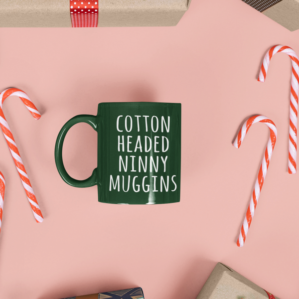 dark green christmas mug with white print that says Cotton Headed Ninny Muggins