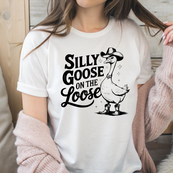 Woman wearing a white graphic t-shirt that says 'Silly Goose on the Loose' with a cartoon goose in cowboy boots and a hat, 