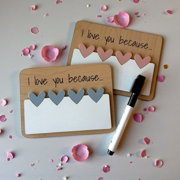 Two wooden cards with heart shapes and a marker on a light surface with flower petals.