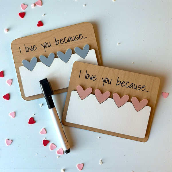 Two wooden boards with 'I love you because' text, heart-shaped cutouts, and a marker on a light blue background.
