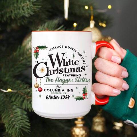 White mug with 'White Christmas' text held in front of a decorated Christmas tree.