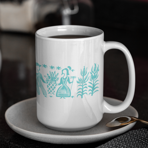 White mug with teal coffee-themed design on a saucer with a blurred coffee shop background