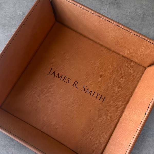 Brown leather tray with 'JAMES R. SMITH' engraving on a gray surface